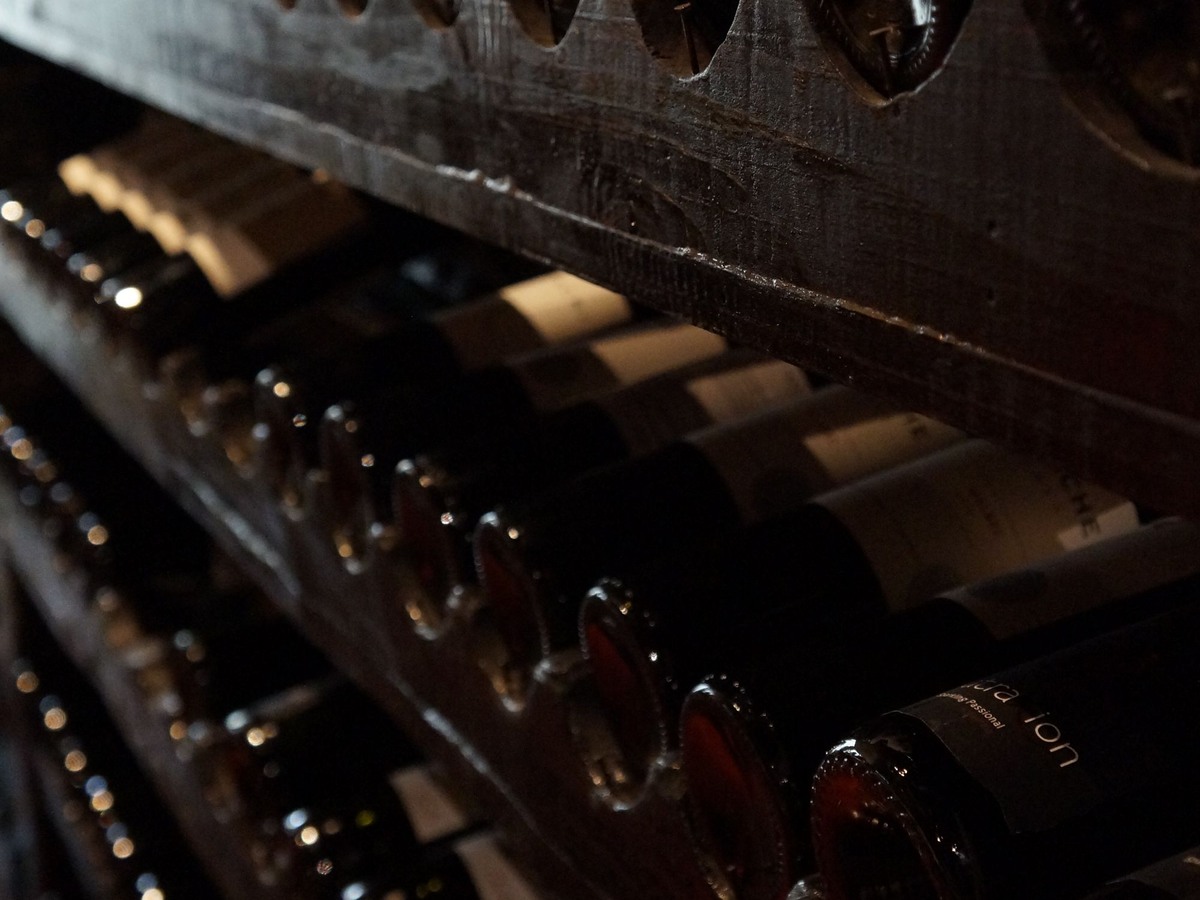 Bouteilles de vin couchées sur des casiers en bois dans une cave faiblement éclairée